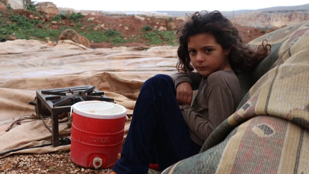 طفلة سورية بعمر السابعة تجلس على بقايا خيمة عائلتها بعدما اقتلعتها العاصفة