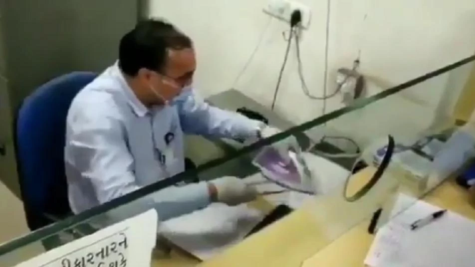 مشاهد طريفة لتعامل موظف هندي في بنك مع العملاء لوقاية نفسه من كورونا (فيديو)